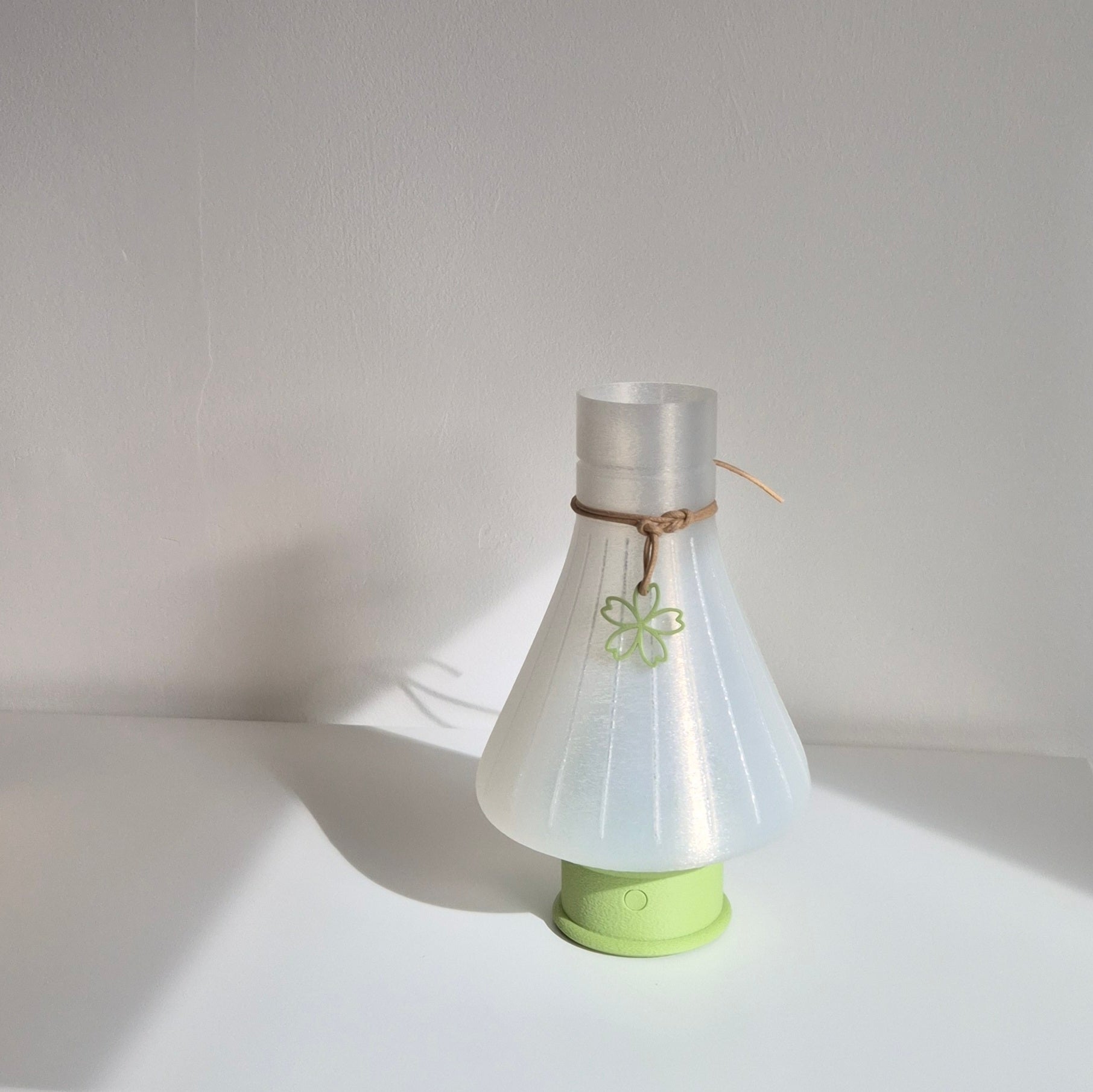 Translucent lamp shaped as matcha whisk, with cord and green base